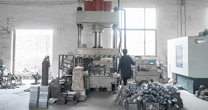 Worker operating machinery in a factory, surrounded by car exhaust system components including catalytic converters and mufflers, showcasing the manufacturing process.